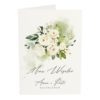 Front menu weselnego z białymi kwiatami i zielonymi listkami na białym papierze