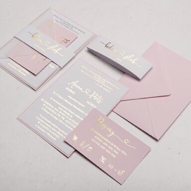 Pudrowe zaproszenie ślubne ze złocona treścią na elementach z przeźroczystą opaską na kopertę